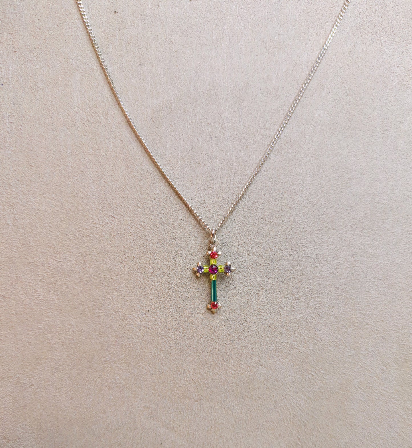 A multicolored cross necklace with a chain link.