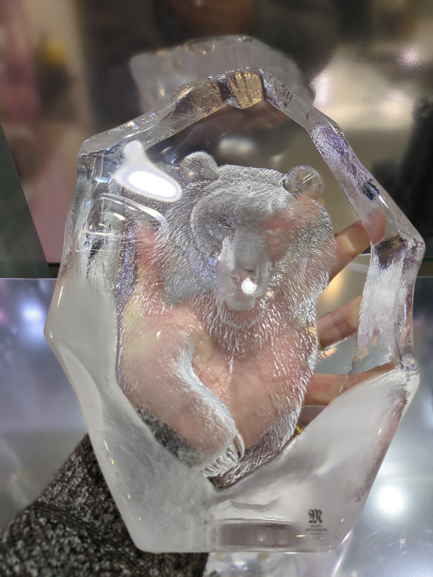 Crystal sculpture of a bear held by hand.