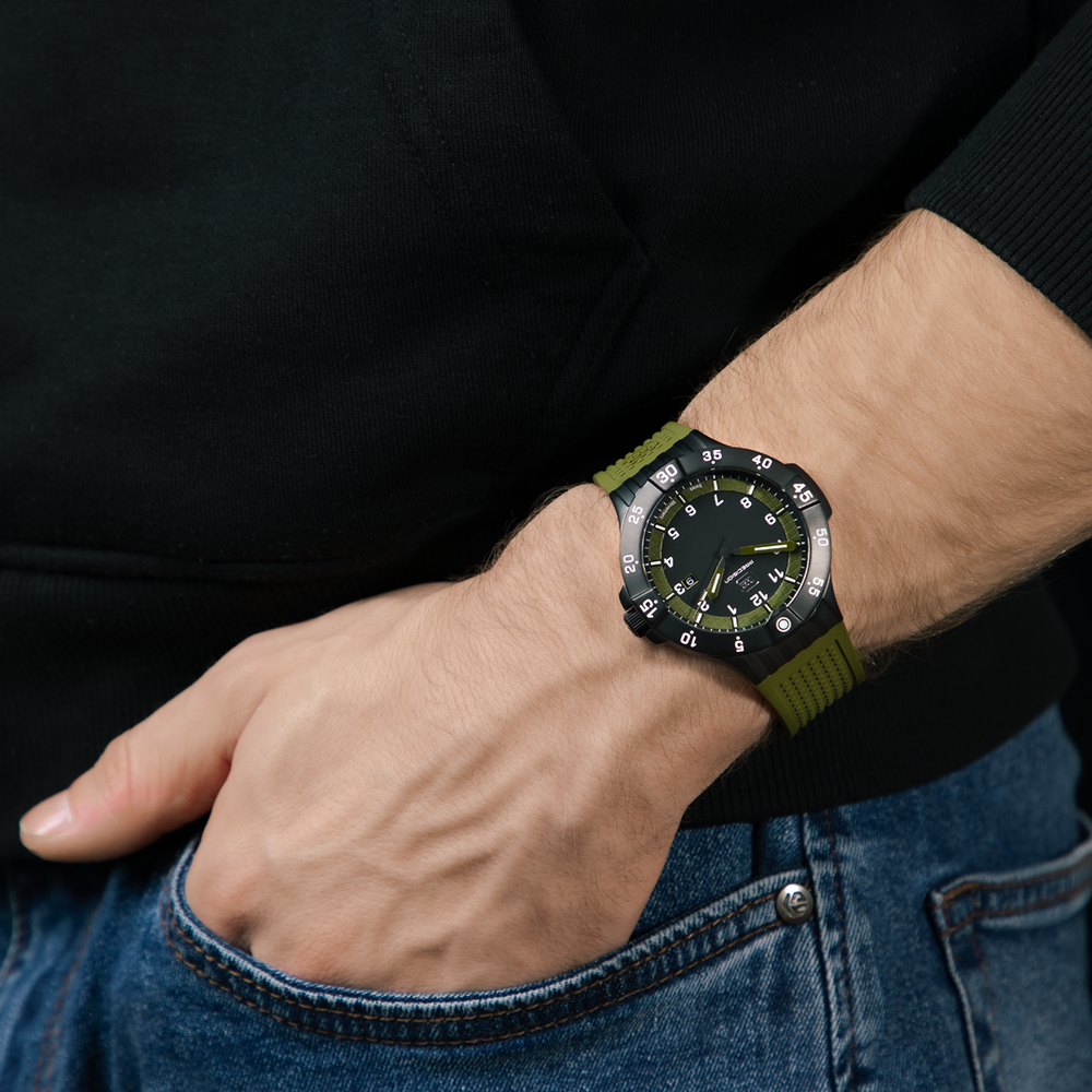 Person wearing a watch with a green strap on a dark background