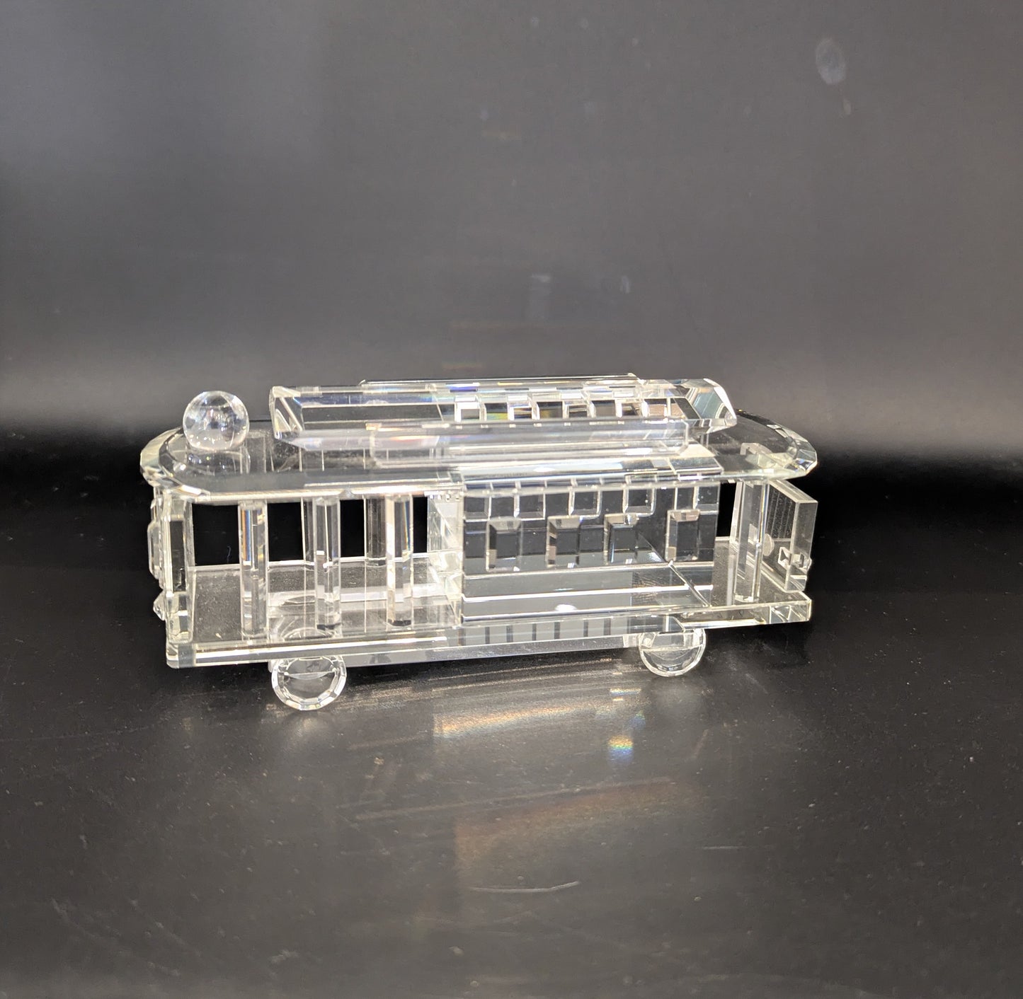 Clear glass model of a tram on a dark surface