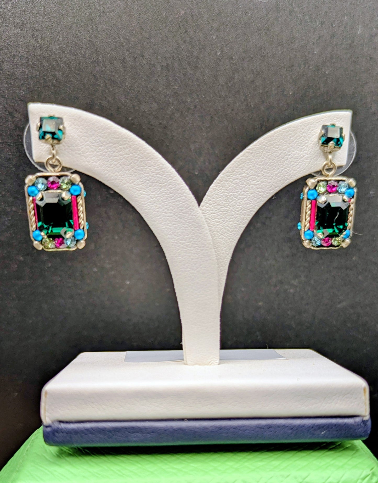 Pair of earrings on a white stand against a black background