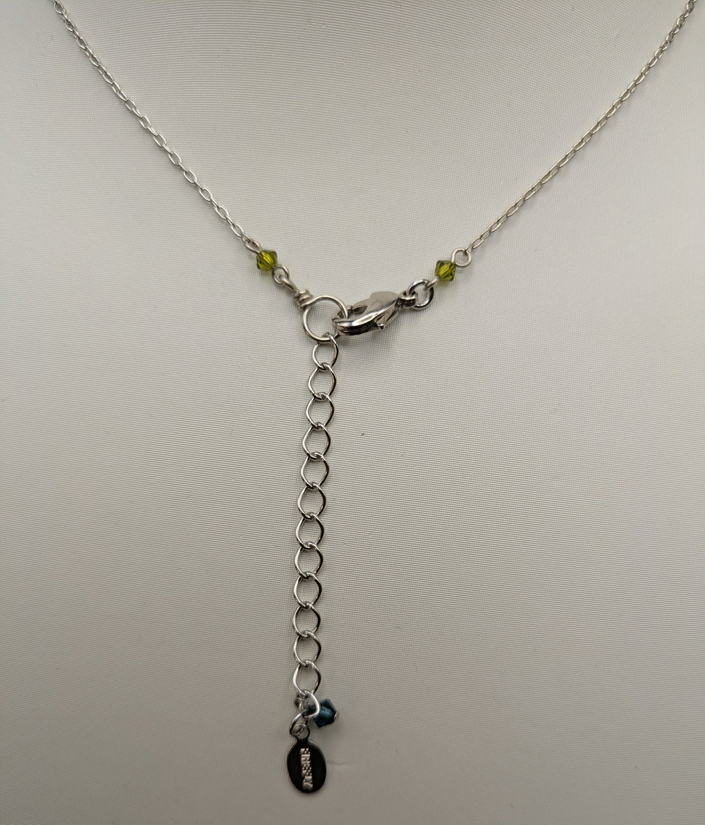 Silver necklace with a chain and pendant on a light gray background