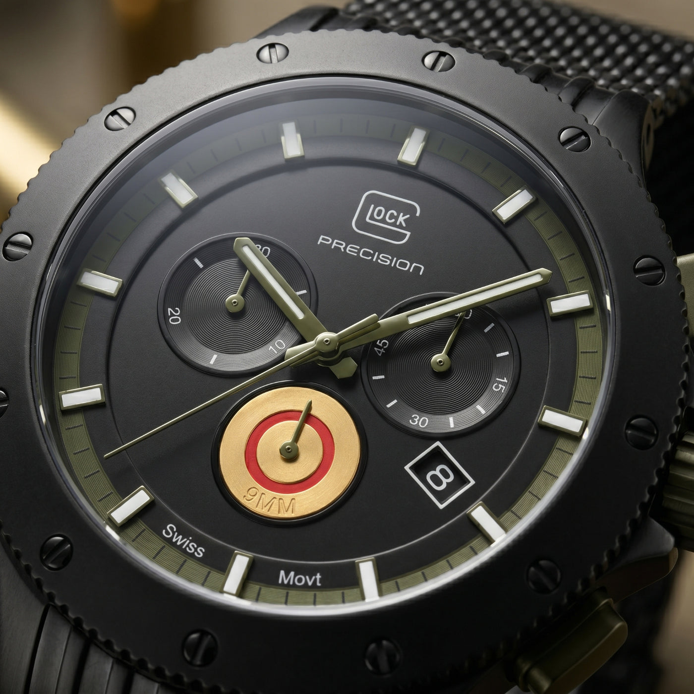 Close-up of a black chronograph watch with a textured bezel, black dial, olive-green subdials, and a gold-toned center accent. The dial shows the brand name 'GLOCK PRECISION' and 'Swiss Movt'.