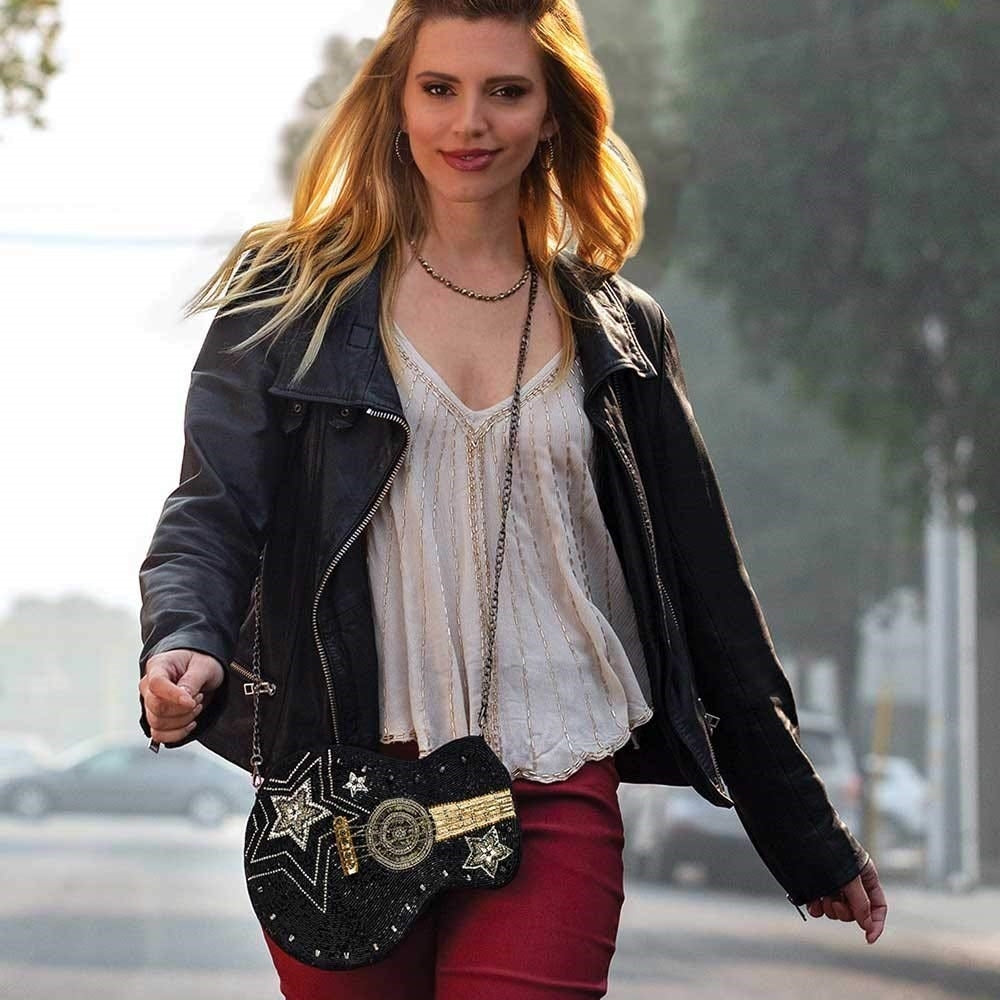 A model is carrying Crossbody Guitar Handbag.