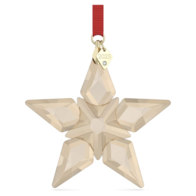 A beige crystal star-shaped festive ornament with a red hanging ribbon and a gold Swarovski branding tag.