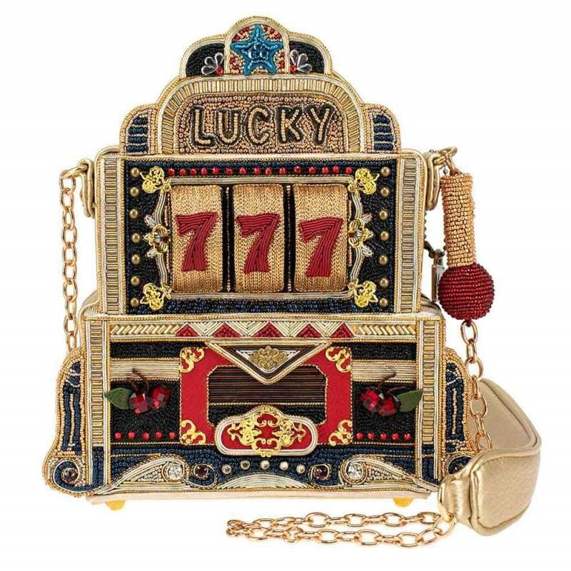 A crossbody handbag designed to look like a vintage slot machine with a 'Lucky 7' motif, featuring vibrant colors and a sequin finish.
