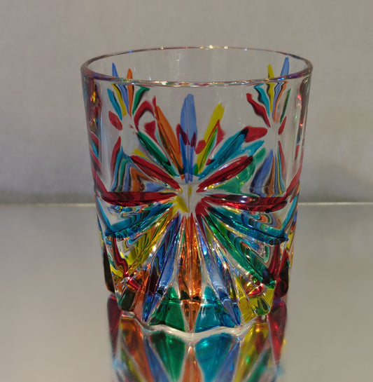 A multicolored, patterned glass whiskey glass reflecting light on its surfaces.