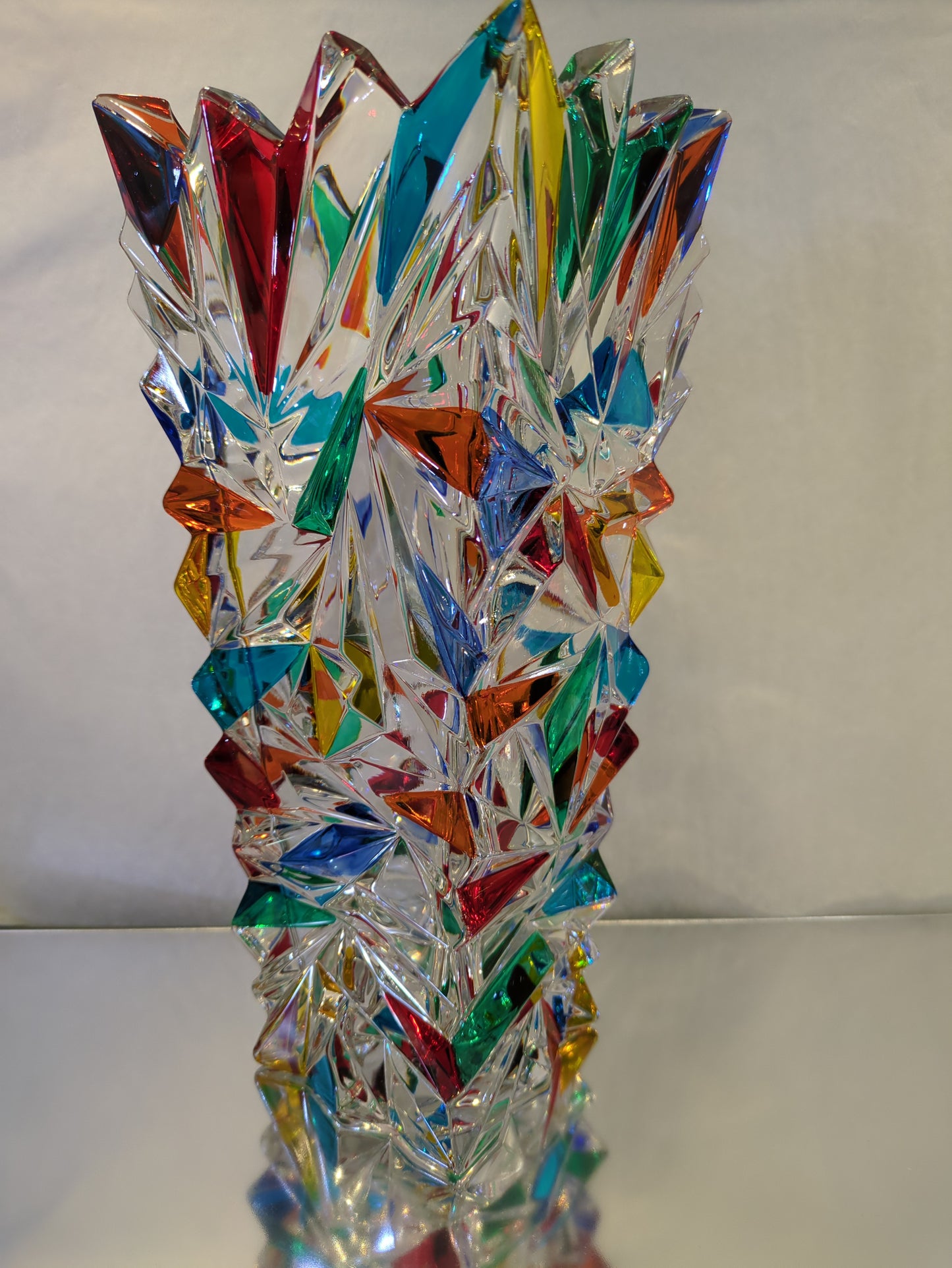 A clear glass vase with multicolored geometric patterns.