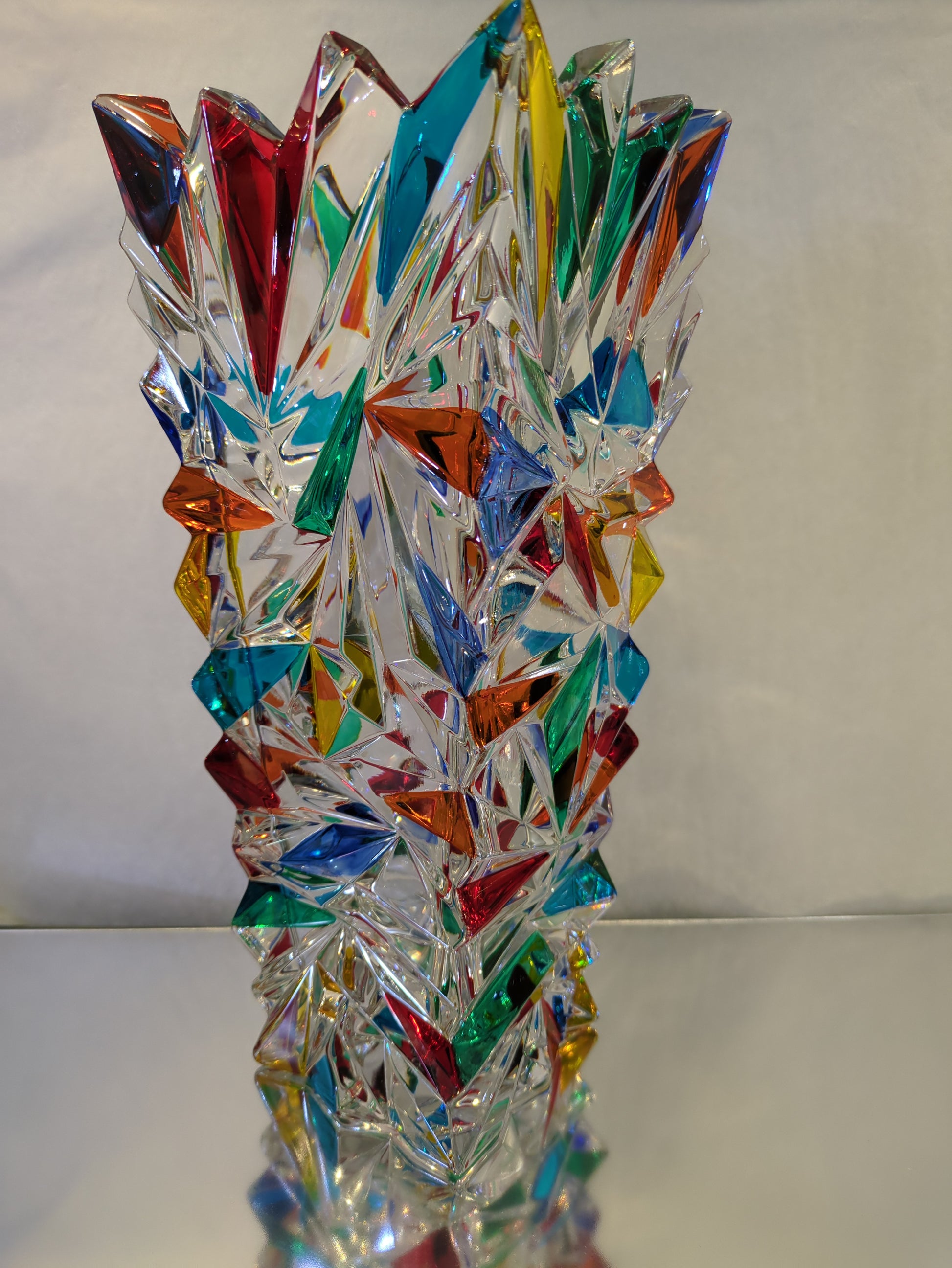 A clear glass vase with multicolored geometric patterns.