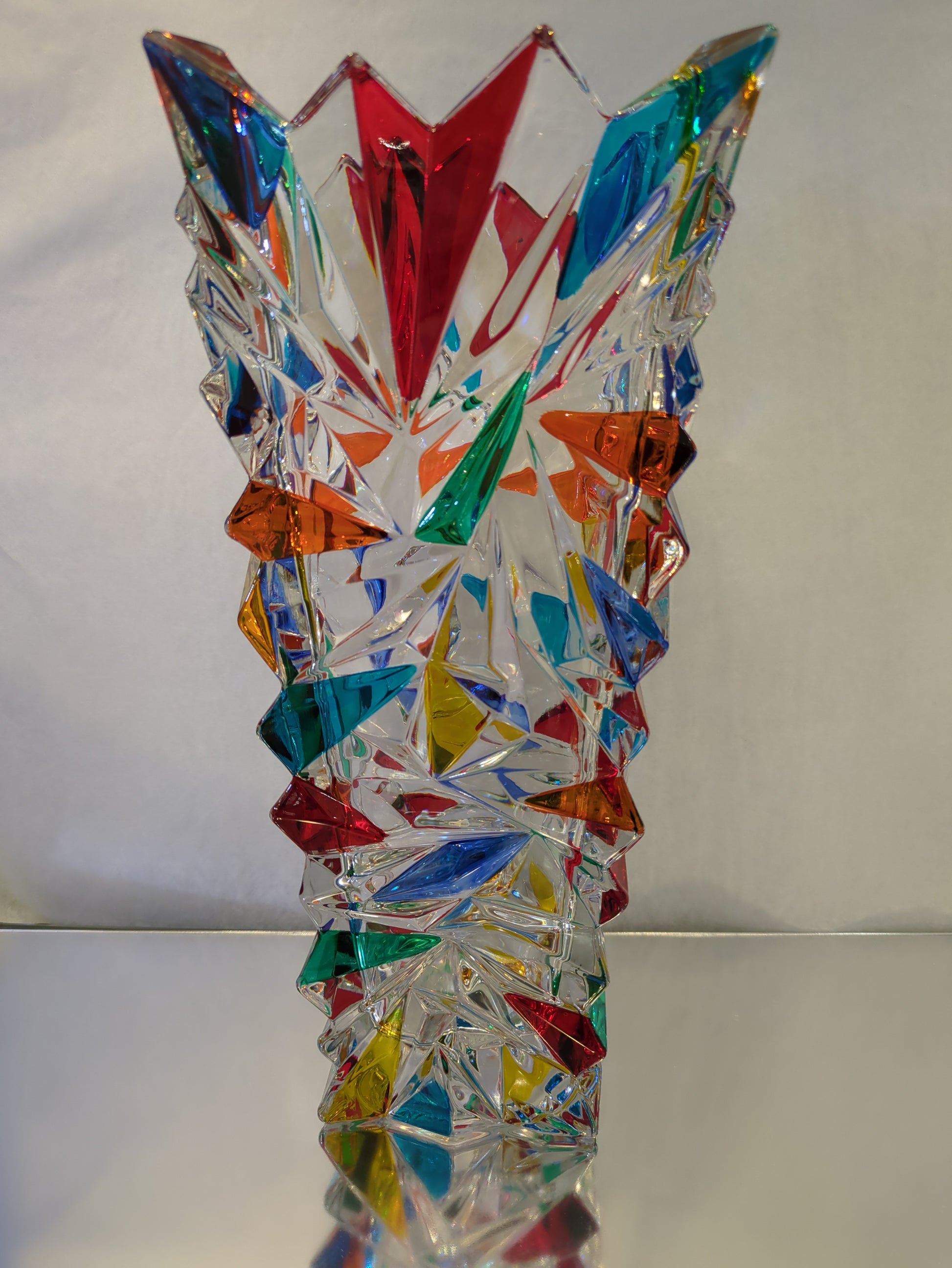 A hand painted art glass vase with a geometric pattern featuring multiple colors.