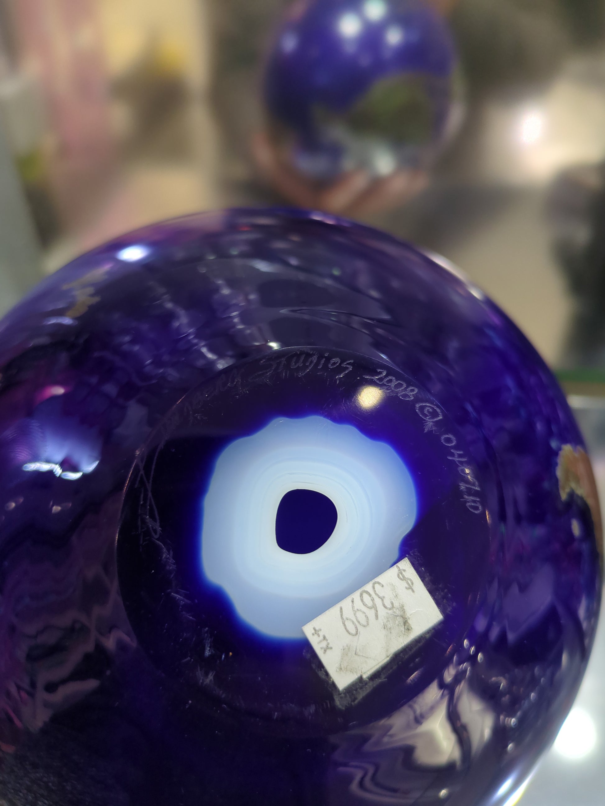 Close-up of a purple glass object with a label on a blurred background