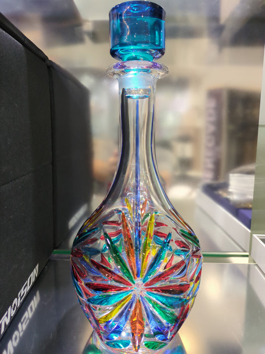 Colorful glass decanter with a blue accent on a reflective surface