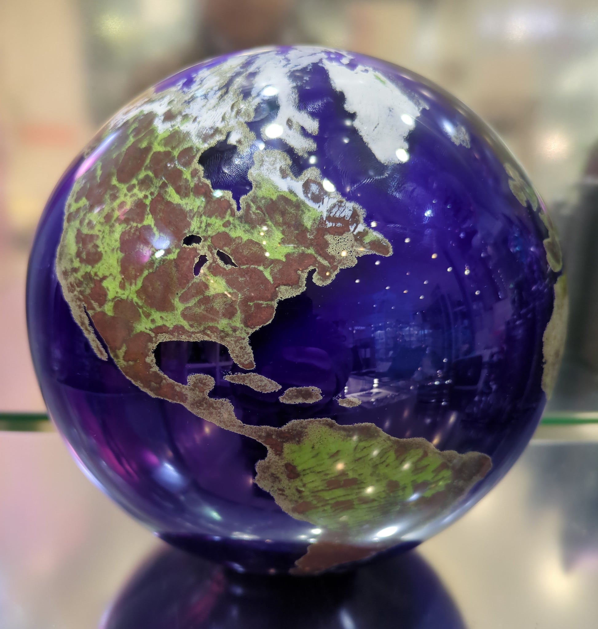 Glass marble with Earth map design on a reflective surface