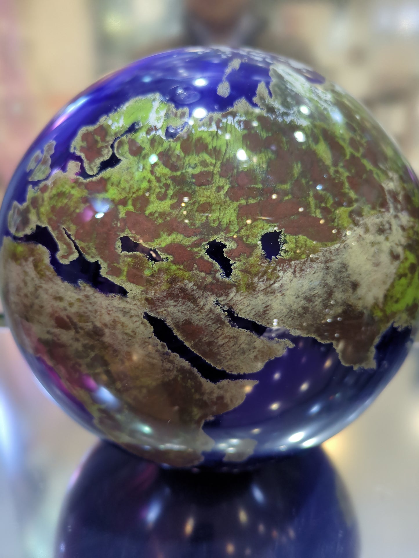 Close-up of a glass paperweight with a world map design on a blurred background