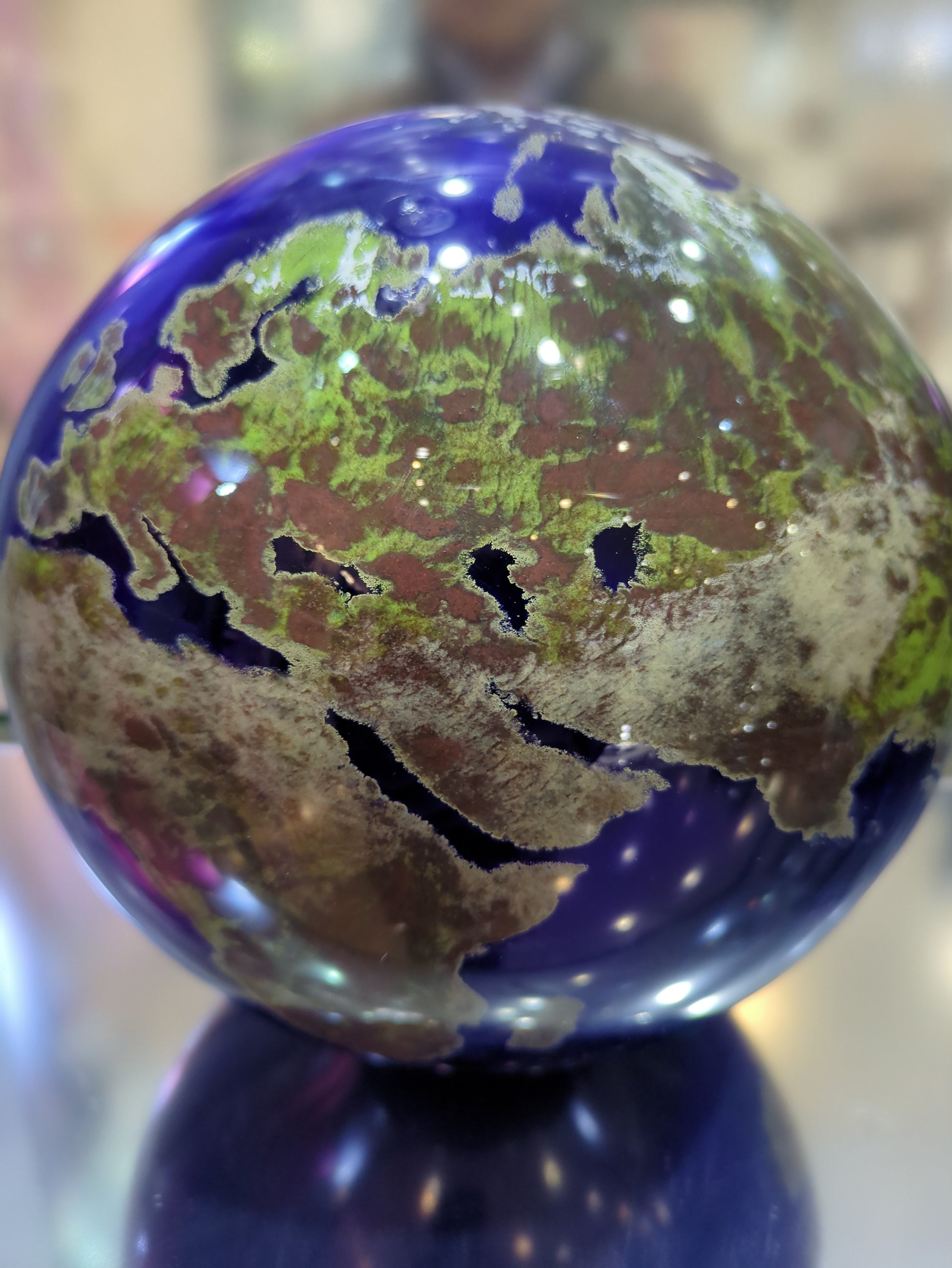 Close-up of a glass paperweight with a world map design on a blurred background