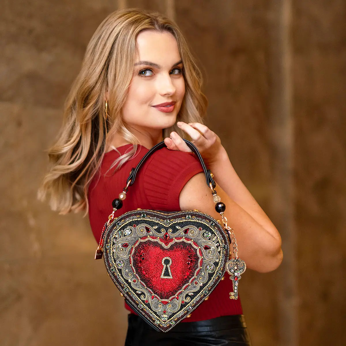 A model is holding a heart shapped hand bag.