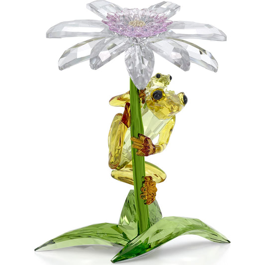A crystal figurine featuring a mother and baby frog sitting under a bright daisy flower, with green leaves at the base. The frogs are yellow and green with the flower predominantly in white and yellow colors.