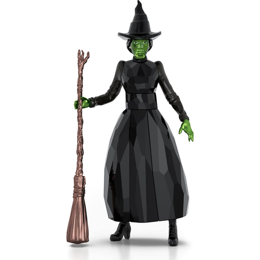 Action figure of a witch with green skin, black outfit, and broom on a white background