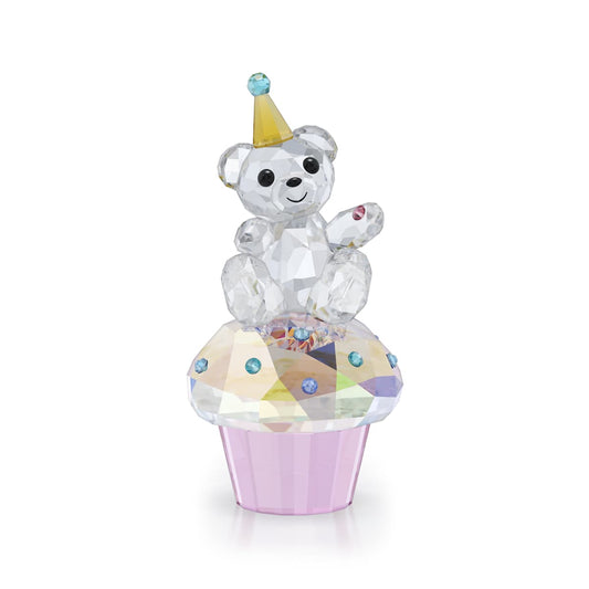 Crystal bear figurine on a cupcake with a party hat on a white background