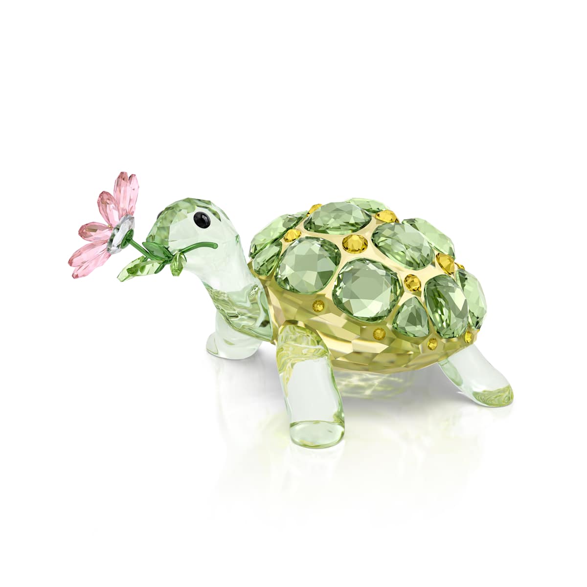 Crystal turtle figurine with green gemstones and a pink flower on a white background