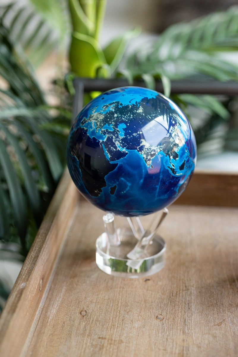 A 6-inch MOVA globe depicting the Earth at night displayed next to the plant.