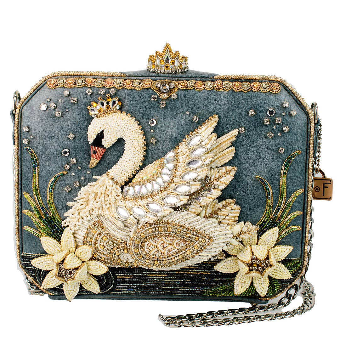 An ornate evening clutch bag featuring a large beaded swan design on a dark teal-blue textured background, embellished with gold-tone rhinestones, a small crown at the top, floral motifs, and a silver chain strap.