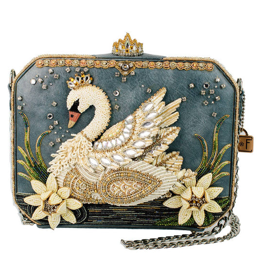 An ornate evening clutch bag featuring a large beaded swan design on a dark teal-blue textured background, embellished with gold-tone rhinestones, a small crown at the top, floral motifs, and a silver chain strap.