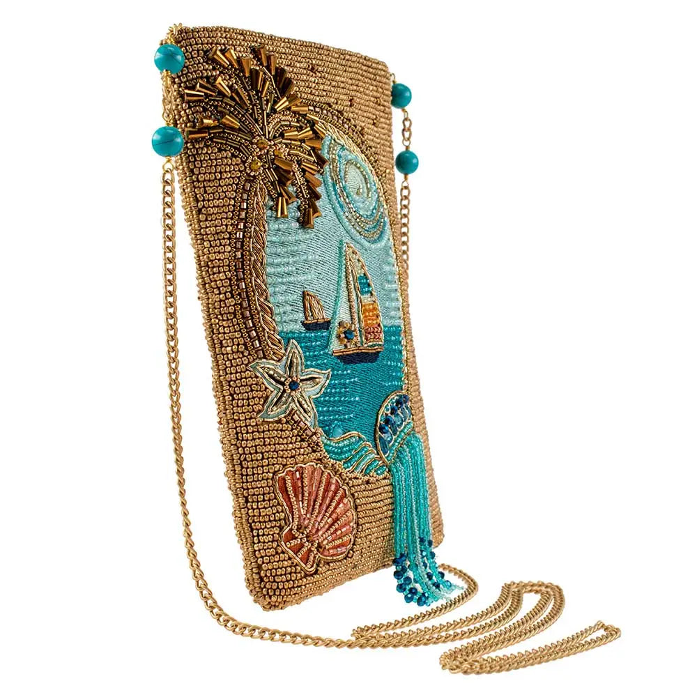 A beige crossbody phone bag with a beaded palm tree and embroidered sailing scene.