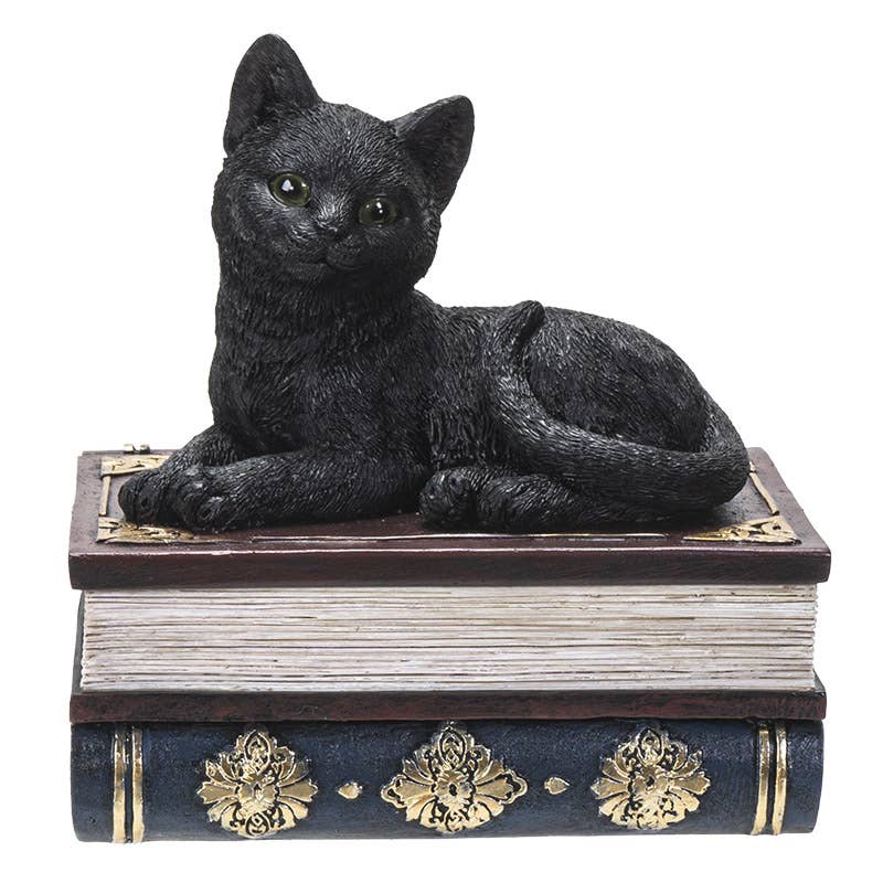 Black cat figurine on top of a decorative book with gold accents