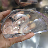 Clear crystal object held by a hand with a blurred background
