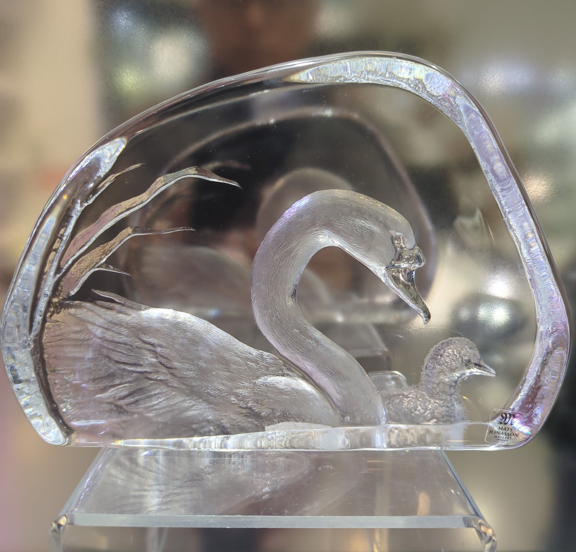 Clear crystal sculpture of a mother and baby swan with intricate detailing on a blurred background