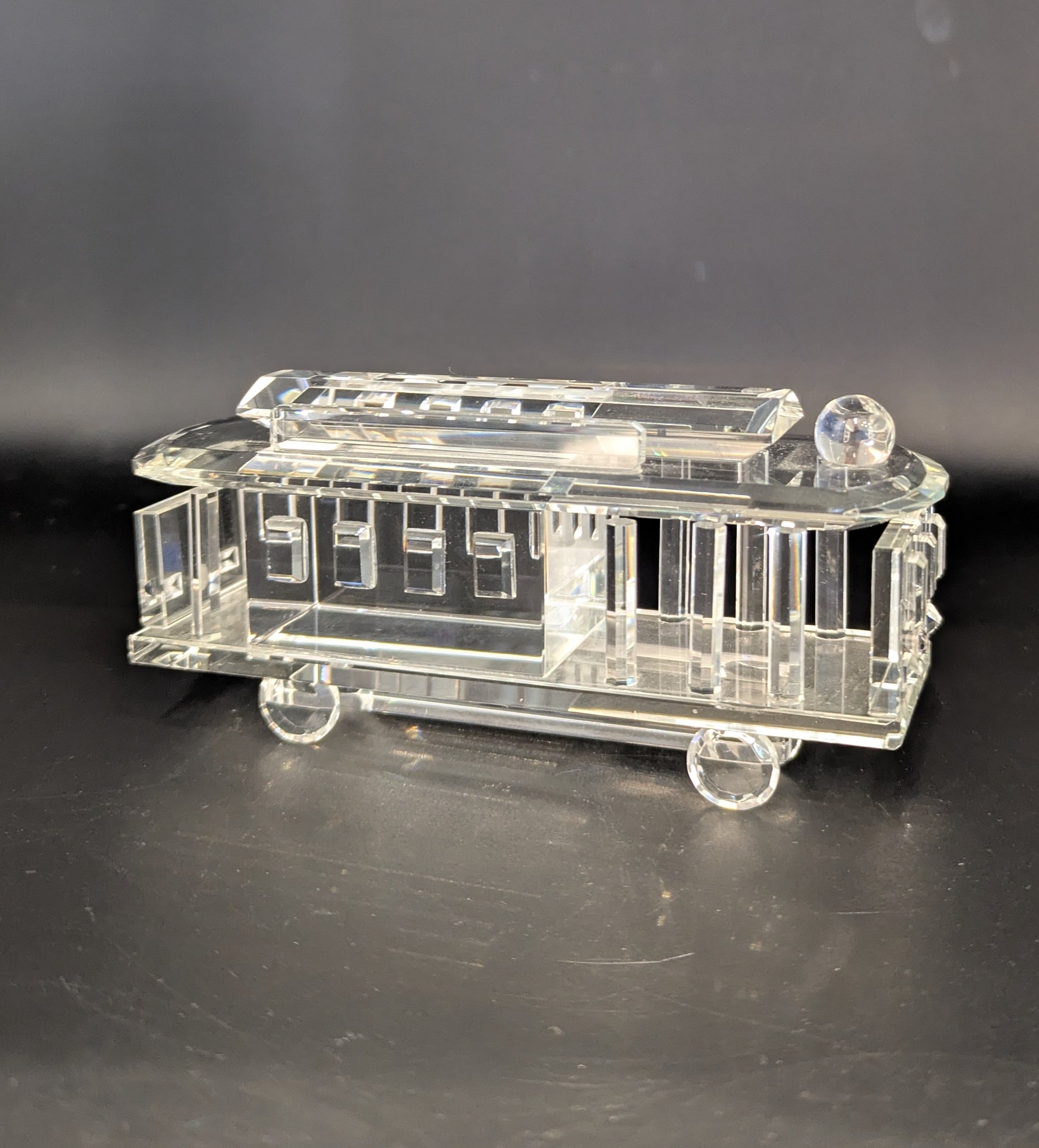 Clear glass model of a tram on a dark background