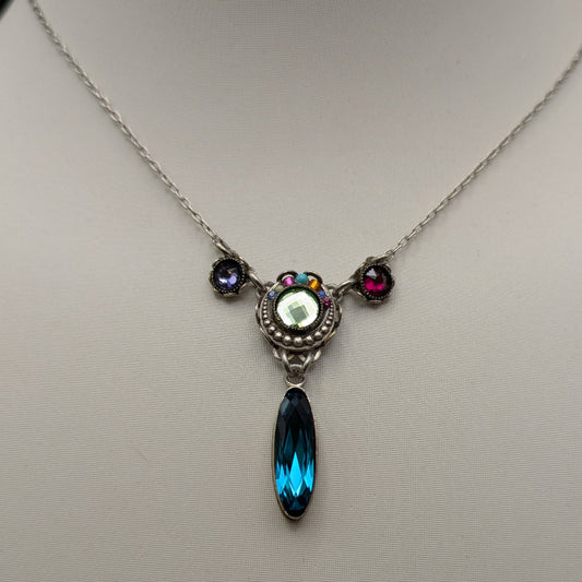 Necklace with a pendant featuring a blue teardrop and multicolored stones on a mannequin.