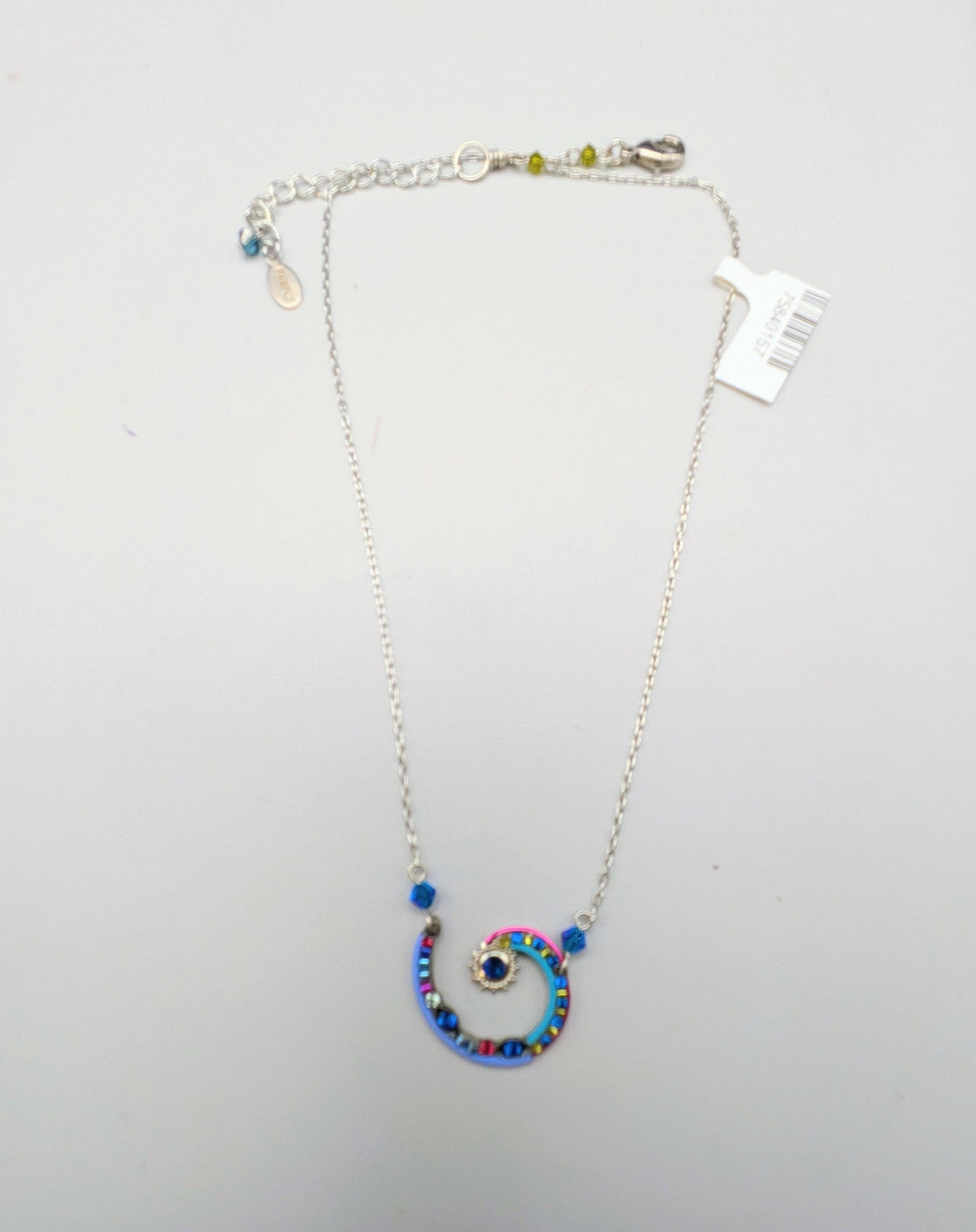 A silver chain necklace with a spiral pendant decorated with blue, pink, and purple rhinestones, displayed on a white jewelry box.
