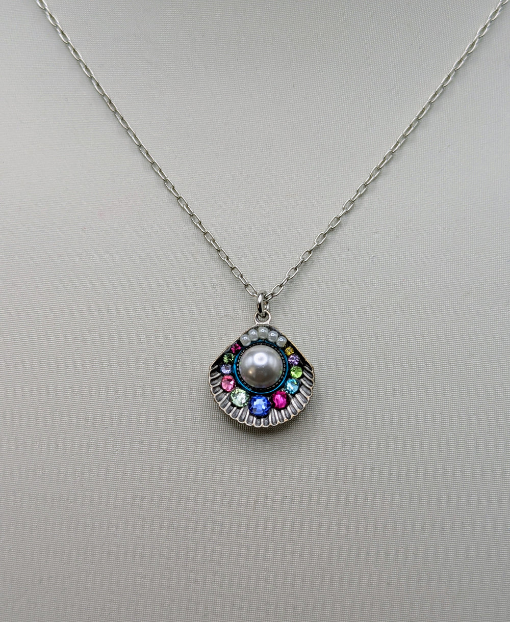 A silver tone chain necklace with a scalloped pendant featuring a central white pearl surrounded by multicolored rhinestones, displayed on a neutral light gray background.