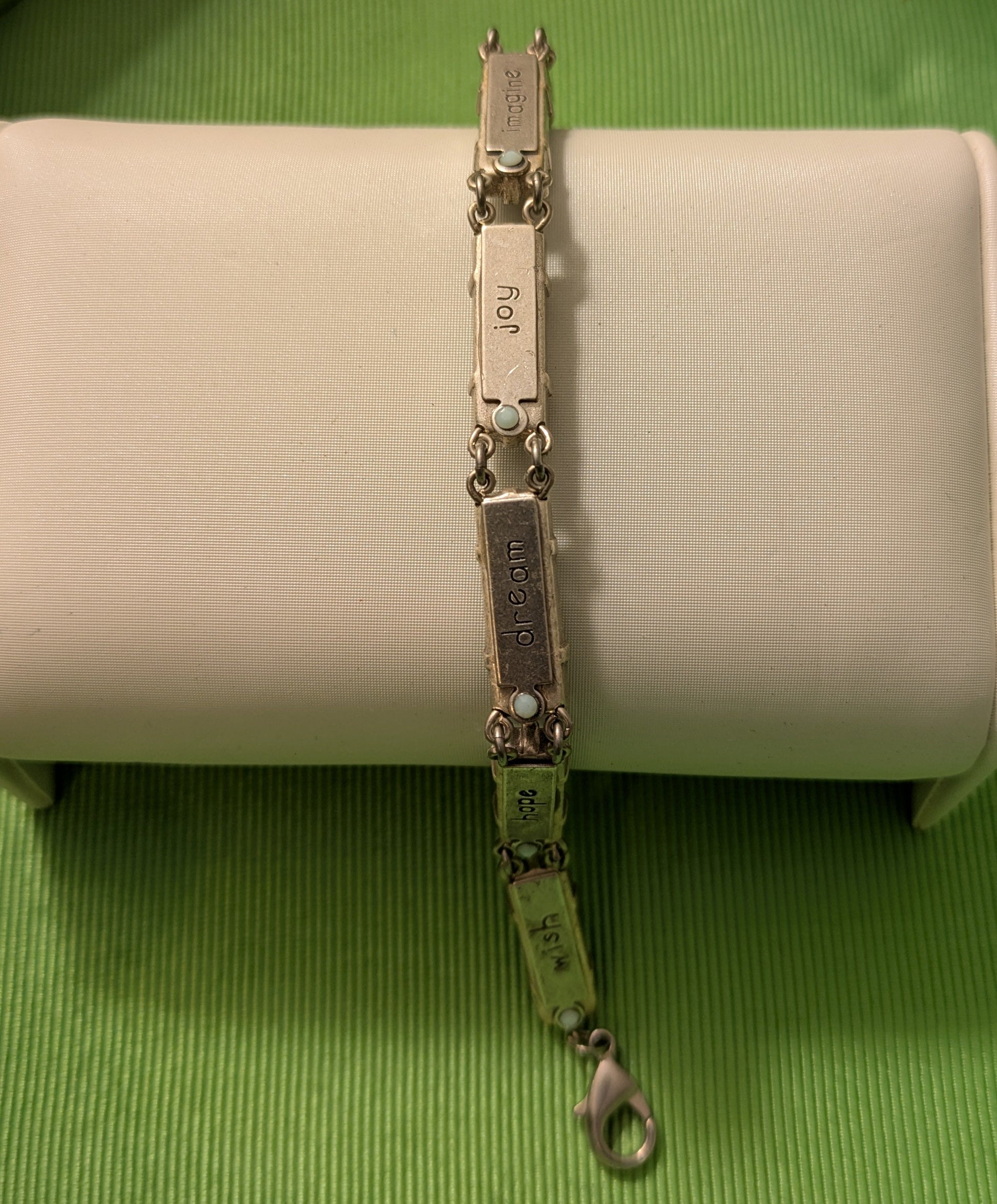 Silver bracelet on a white cushion against a green background