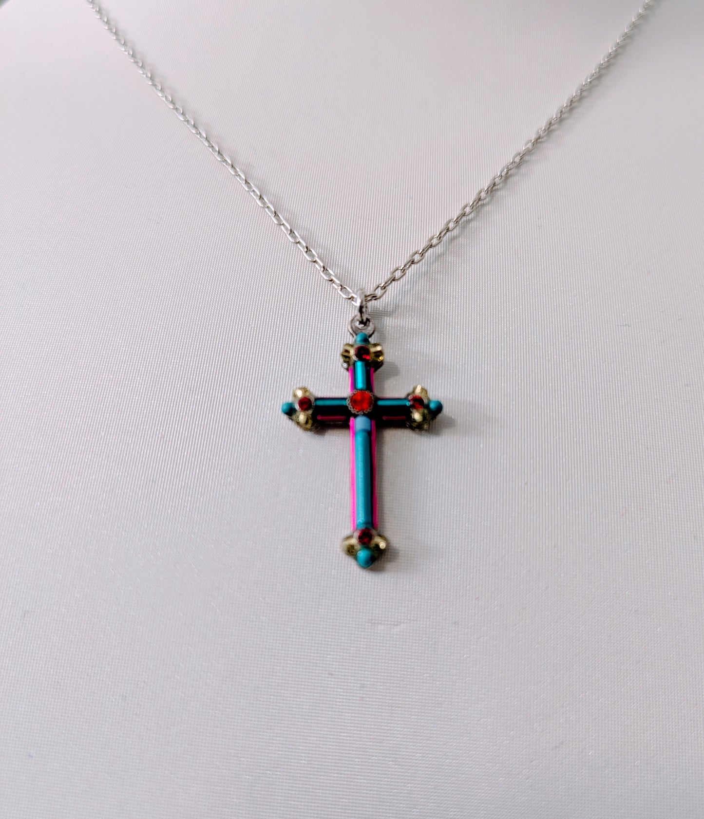 Multicolored cross pendant on a silver tone chain against a white background