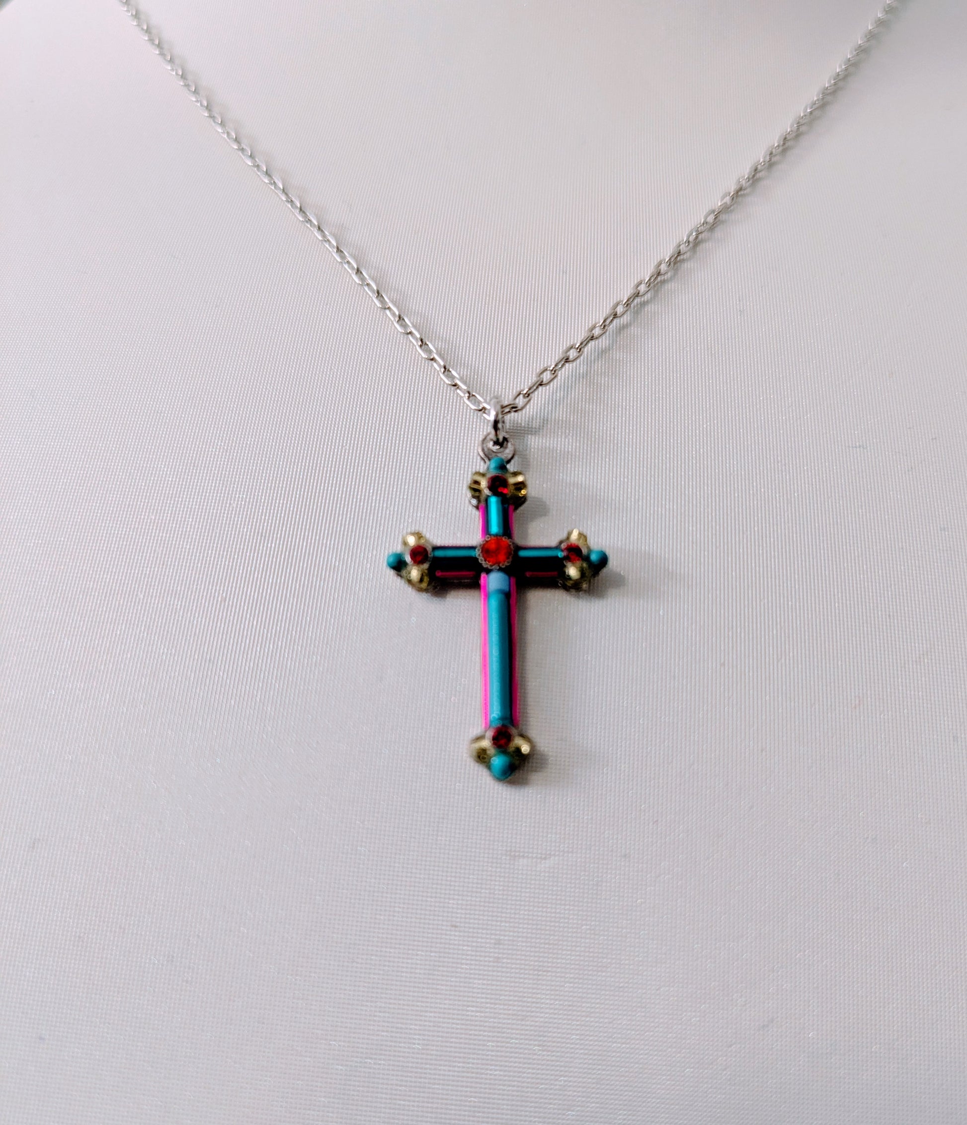 Multicolored cross pendant on a silver tone chain against a white background