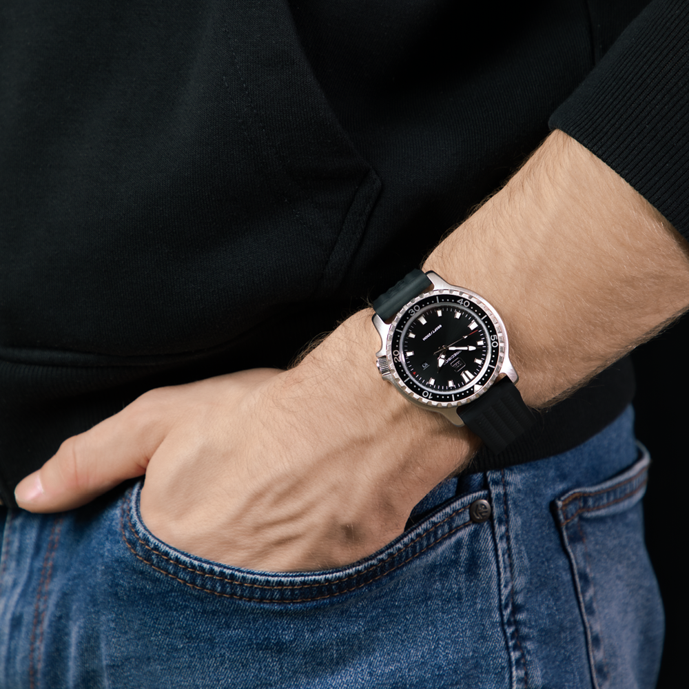 Person wearing a black wristwatch with a black strap on a dark background