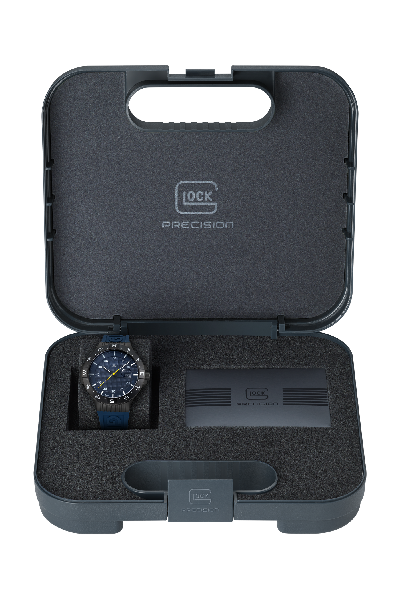 A GLOCK Precision watch with a blue dial and blue strap is displayed inside an open dark gray presentation case with foam insert, alongside a battery or charging module. The case lid is open, showing the G-LOCK PRECISION branding.