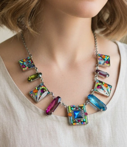 Woman wearing a colorful necklace against a neutral background
