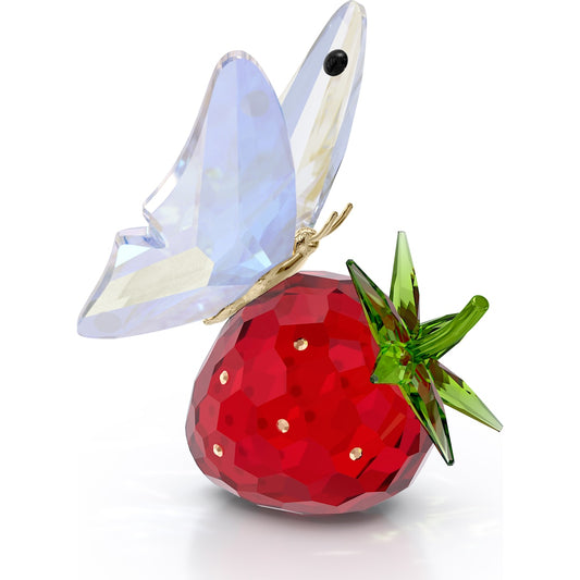 A crystal figurine of a butterfly perched on a strawberry.