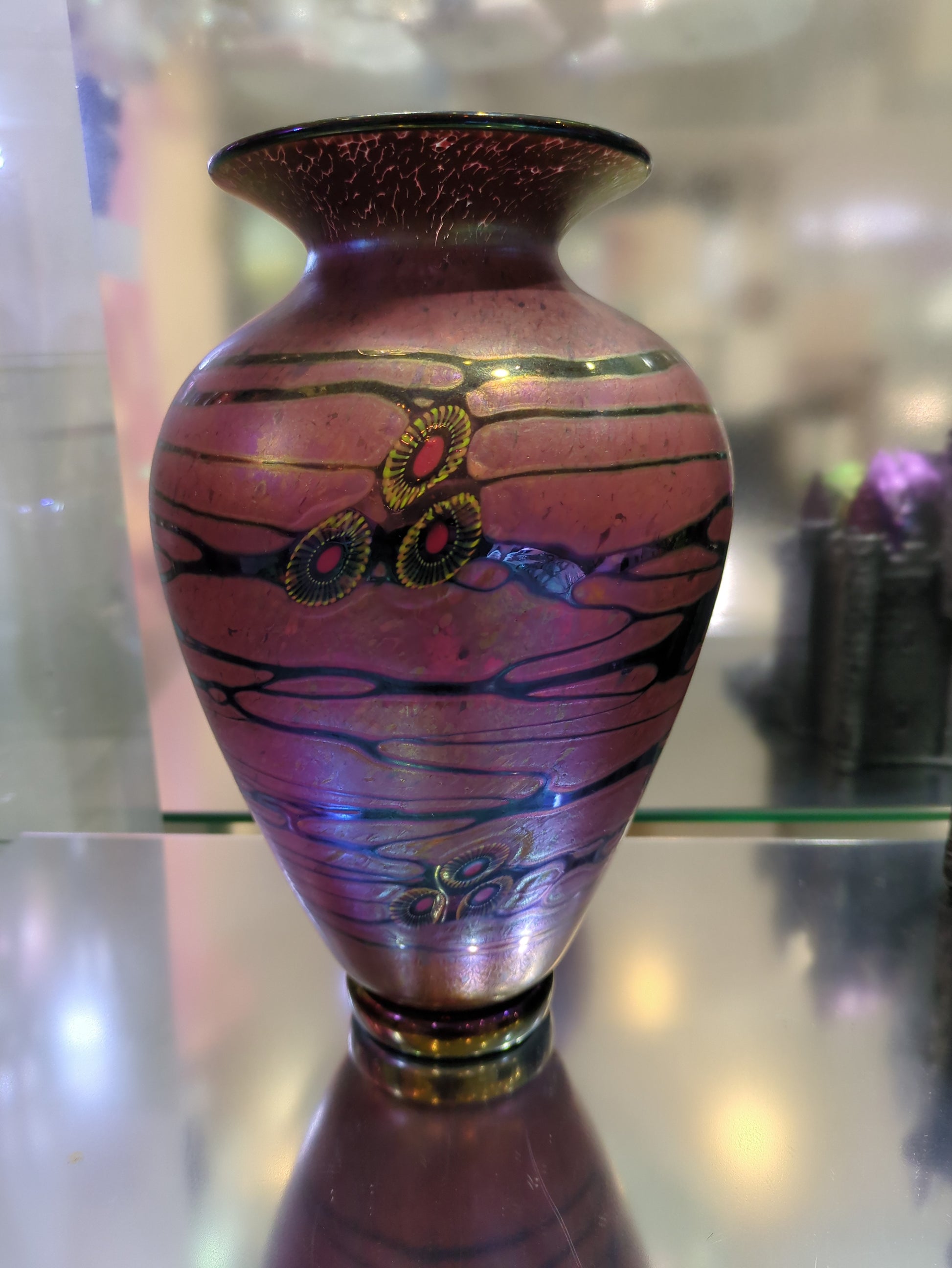 Decorative vase with marbled design and gold accents on a reflective surface