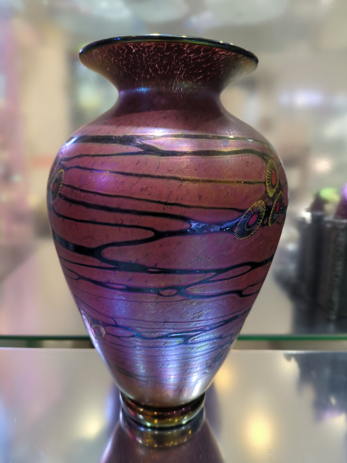 Decorative vase with purple and black patterns on a reflective surface
