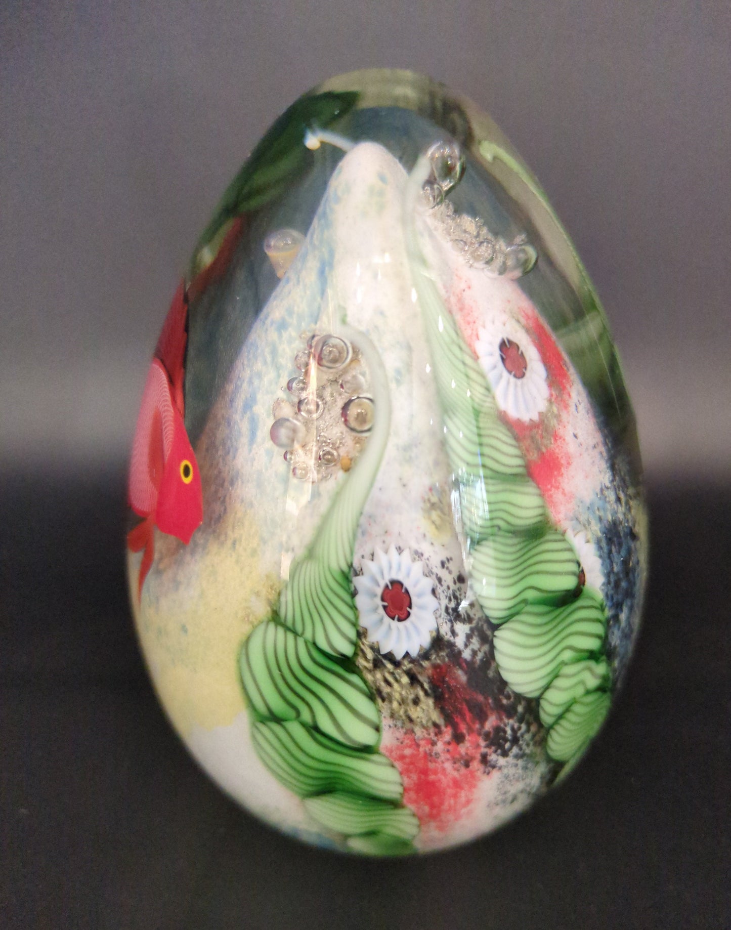 Decorative paperweight with a colorful fish design on a dark background