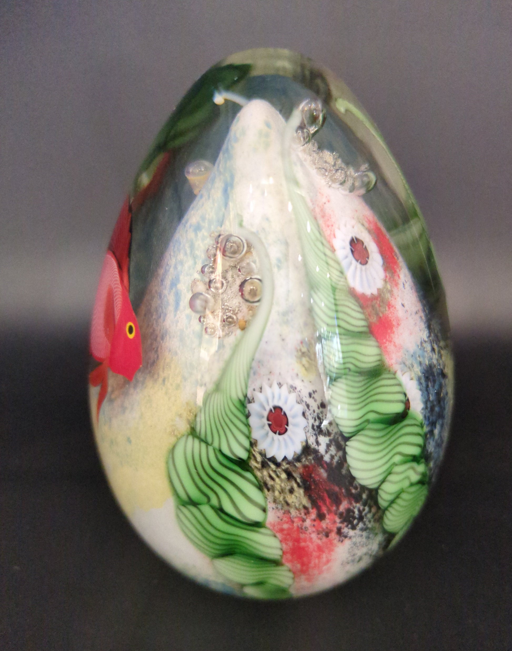 Decorative paperweight with a colorful fish design on a dark background