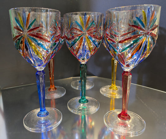 A set of six multicolored wine glasses with a geometric pattern on a reflective surface.