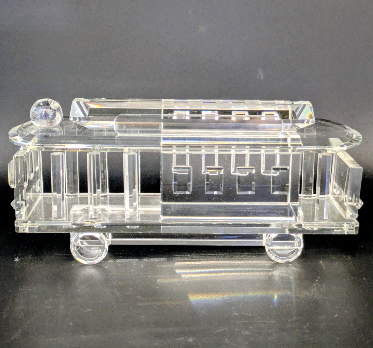 Clear glass model of a tram on a dark background