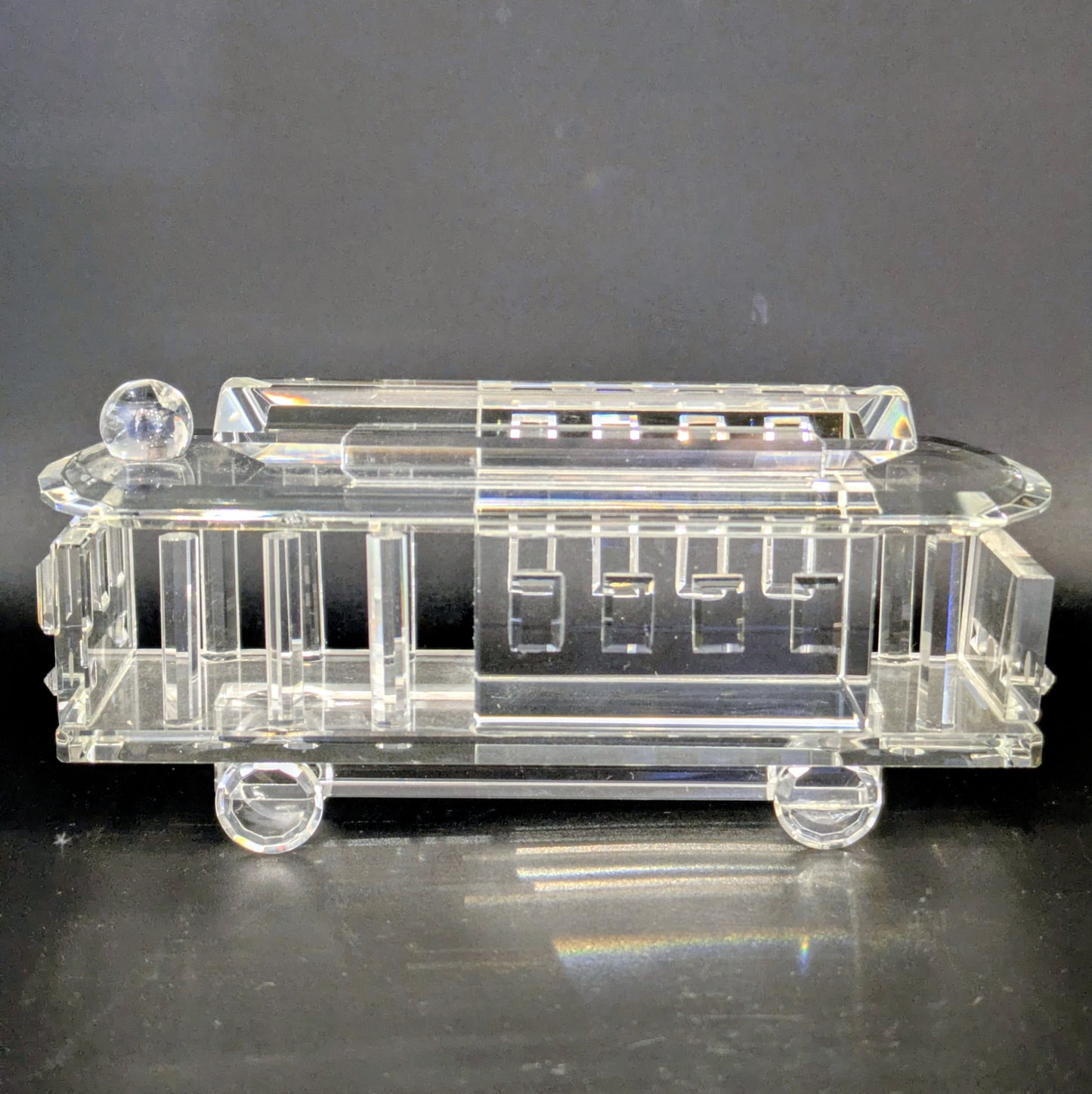 Clear glass model of a vintage car on a dark background