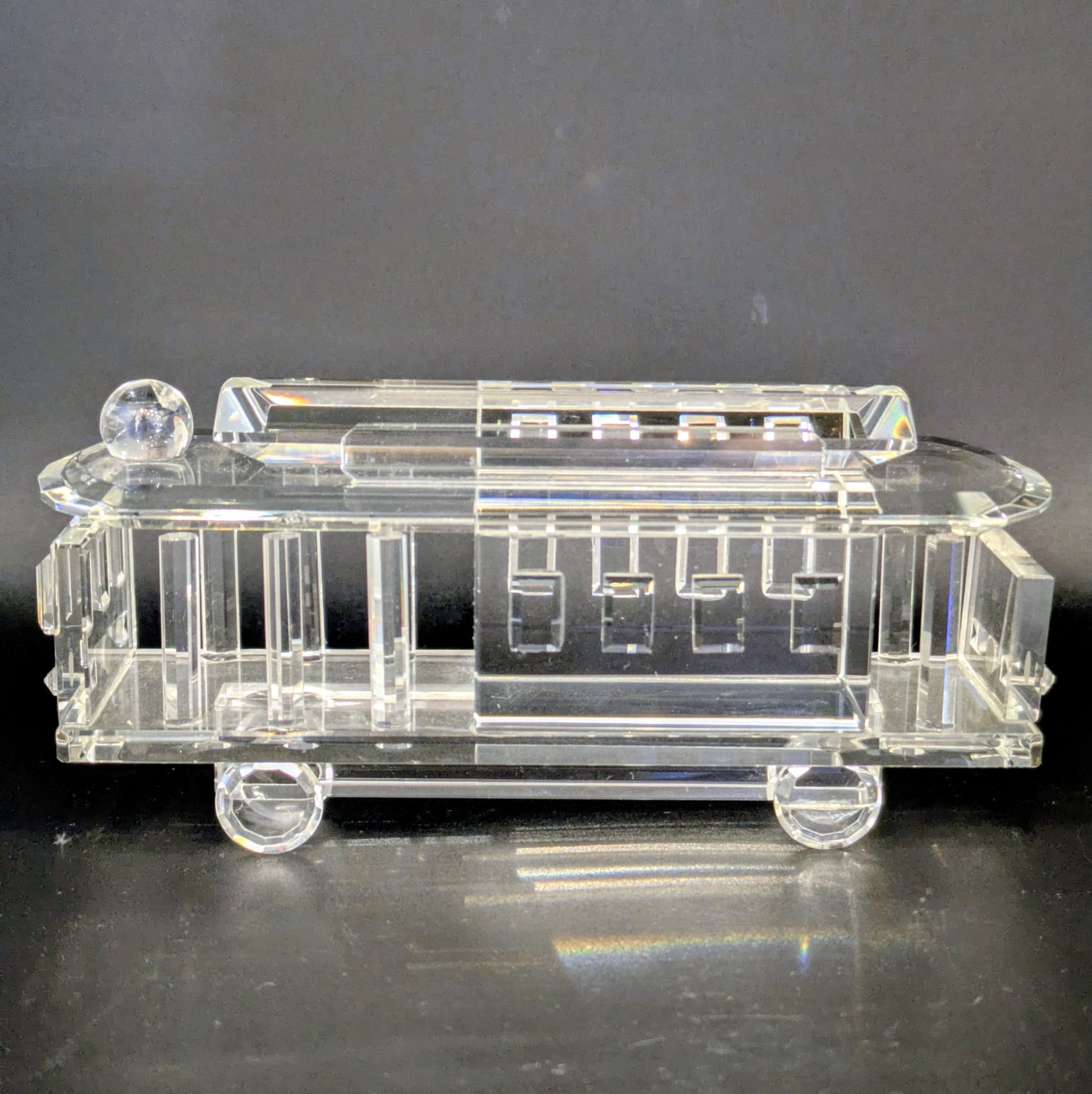 Clear glass model of a vintage car on a dark background